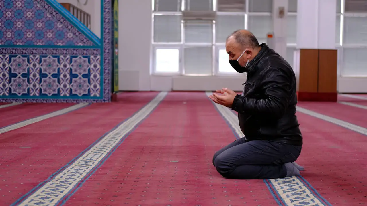 Masked Man Raising His Hands And Praying In Mosque