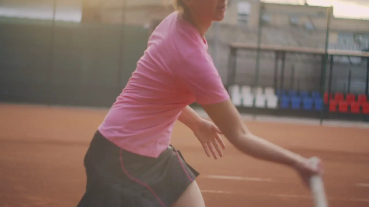 Slow Motion commercial footage of tennis practice through the tennis court net Straight view of a female athlete playing the tennis game A teenage sportsman is hitting the ball during sport training