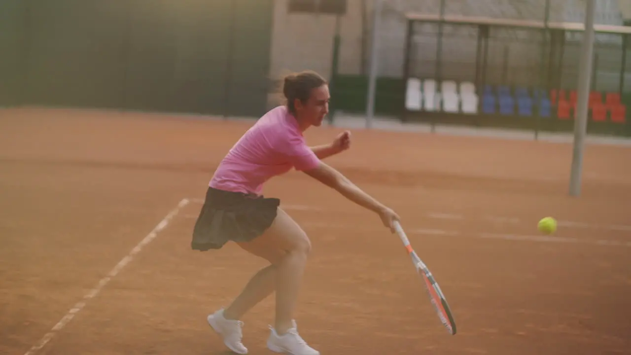 A young brunette tennis player plays a ball at sunset on a tennis court A woman plays tennis professionally and dynamically in slow motion