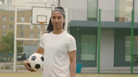 Portrait Of Young Woman Holding Football On Artificial Soccer Pitch In Urban City Area 3