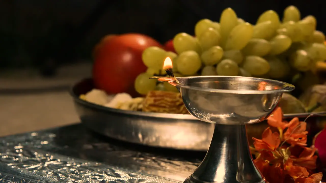 Closeup of light lamps in front of the god with vegitables in the temple during a festival