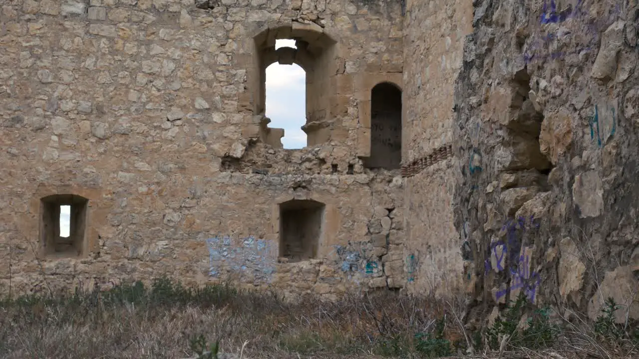 A monk walk in front the camera from right towards left in a ruined castle