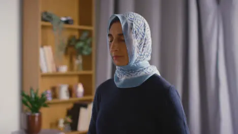 Muslim Woman Wearing Hijab Praying Holding Prayer Beads At Home