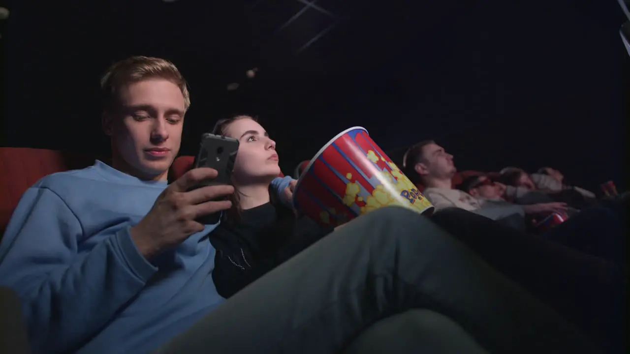 Young man using smartphone in movie theatre