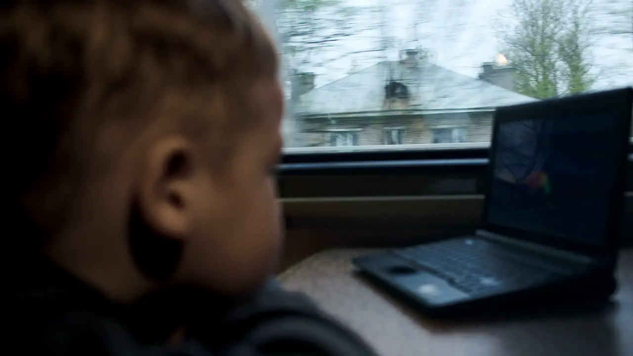 Boy watching movie or cartoon on laptop in the train