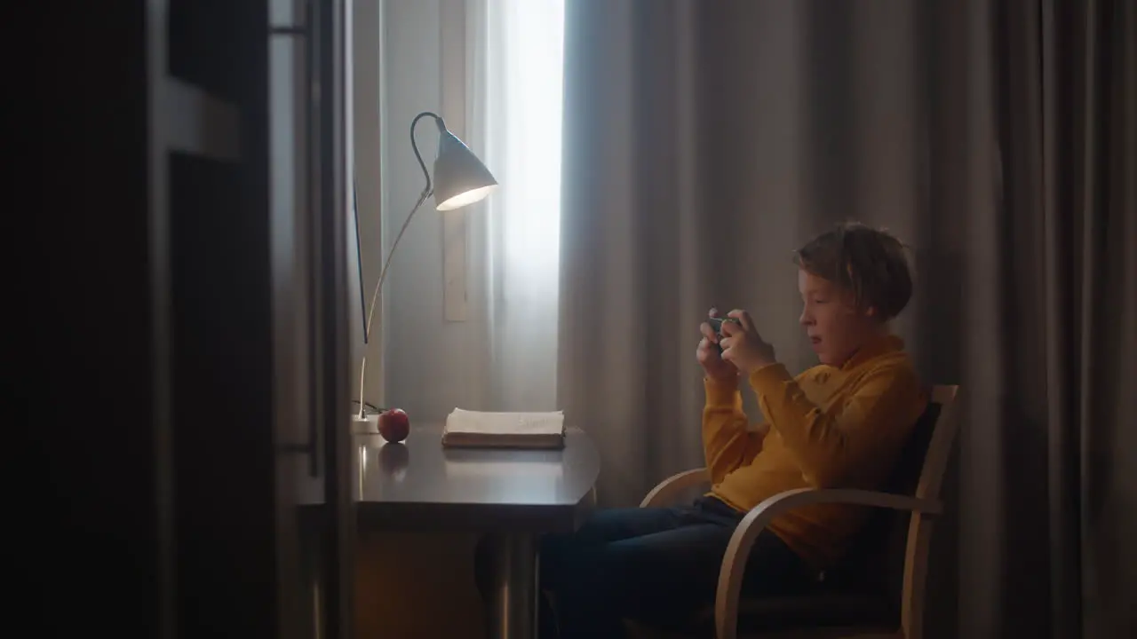 Boy playing on phone at desk