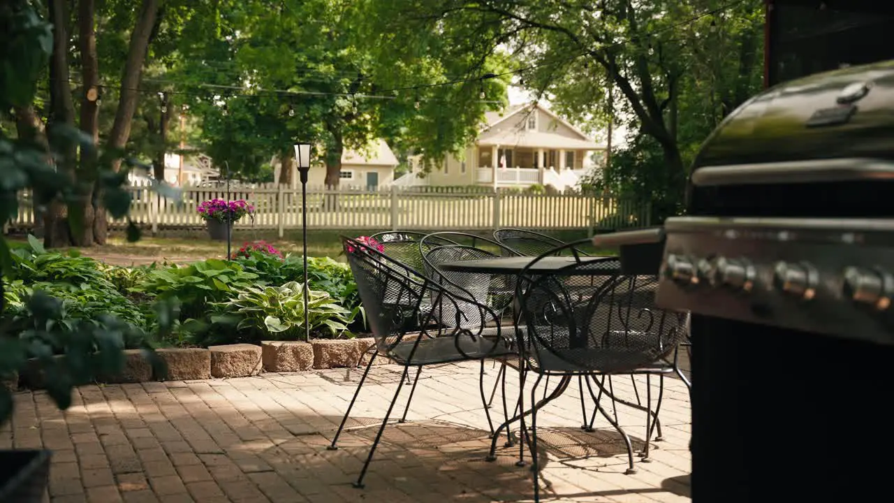 Panning shot of black patio chairs a table and a grill in the foreground