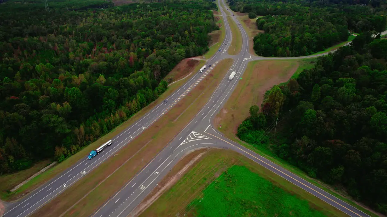 Aerial follow perspective of Semi truck driving on interstate in a densely forested area