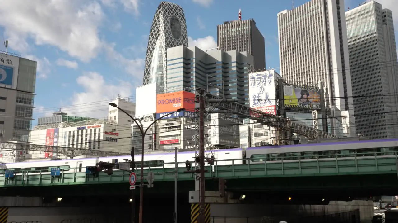 Metro Train Going Past On Elevated Train Track On Sunny Day With Shinjuku Cityscape Building In Background