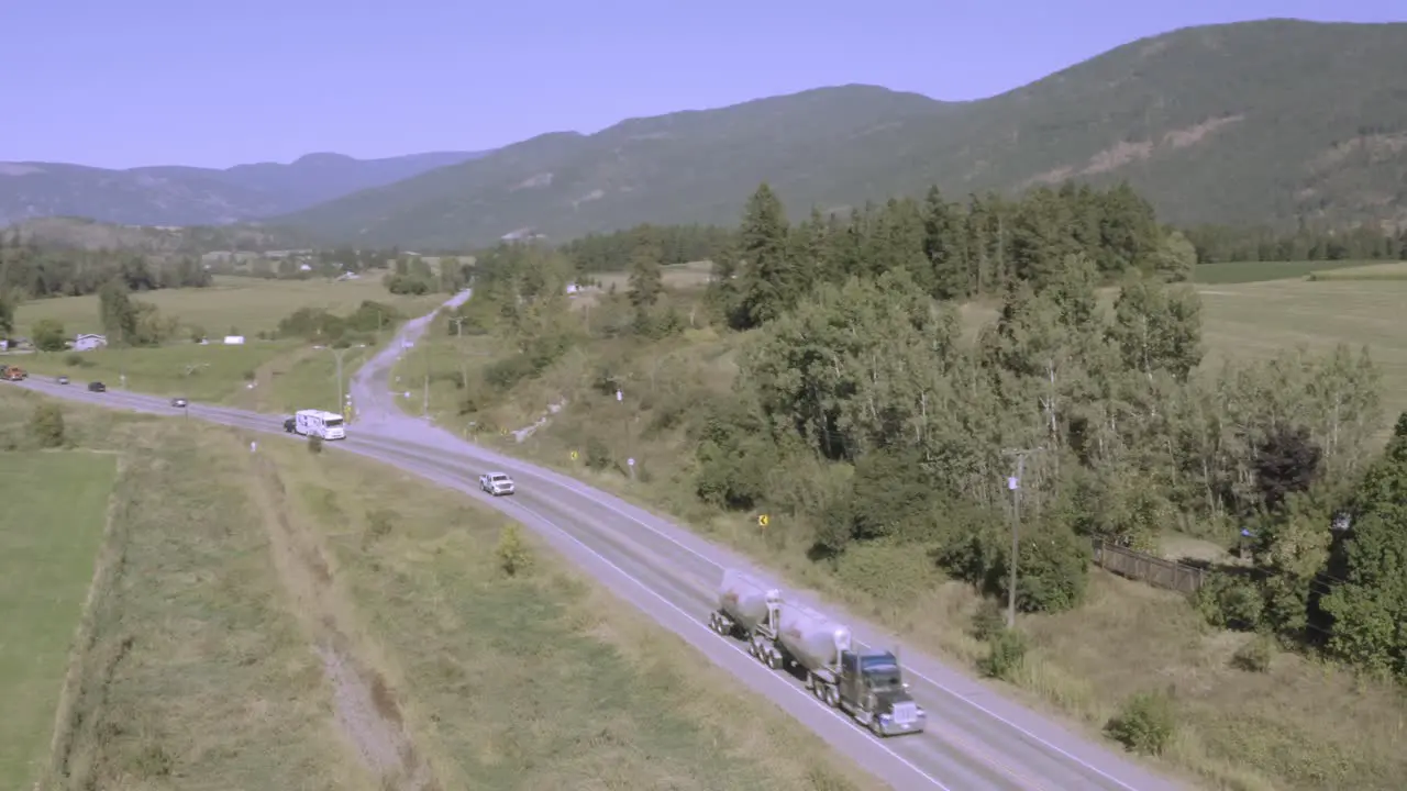 Mountain valley highway freeway interstate following a silver white generic fuel double tanker truck gas carrier trailed by a white RV motorhome towing a vehicle on a clear hot summer day MH1-2