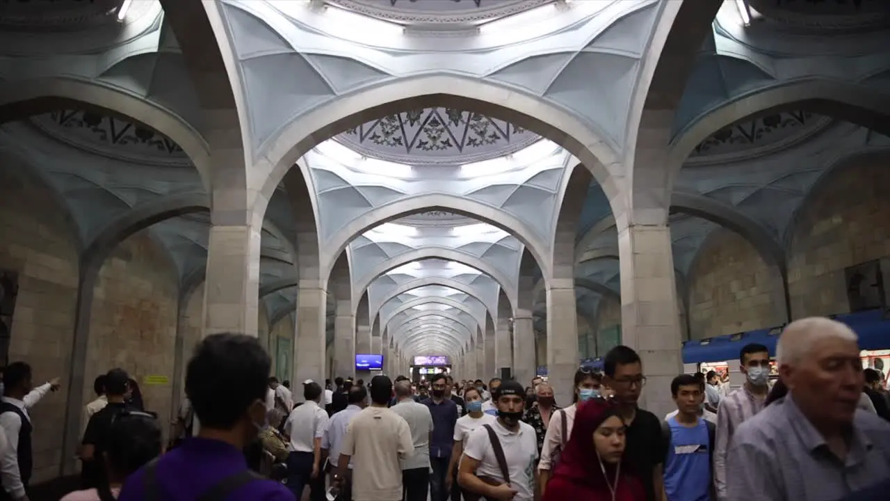 a group of people walking with masks on through a train station in Tashkent Uzbekistan slow motion close up