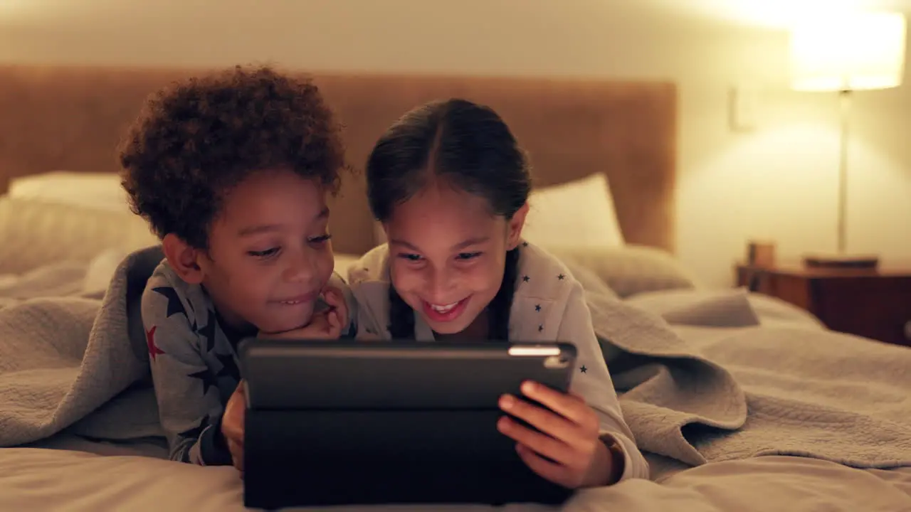 Children watching and video on tablet on bed