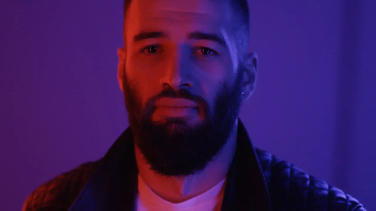 Portrait Of The Attractive Young Cool Guy Touching Of The Collar Of Leather Black Coat And Smiling To The Camera In The Pink Neon Light