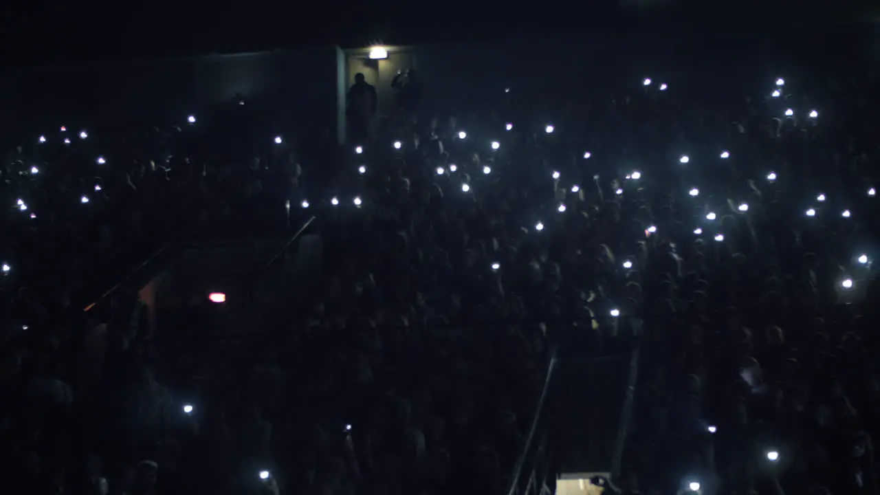 People with lights at the concert in dark music hall