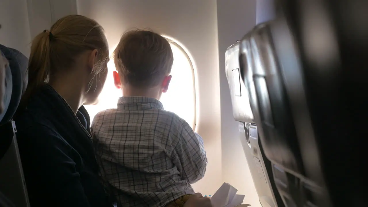 Mother and son looking out illuminator in plane