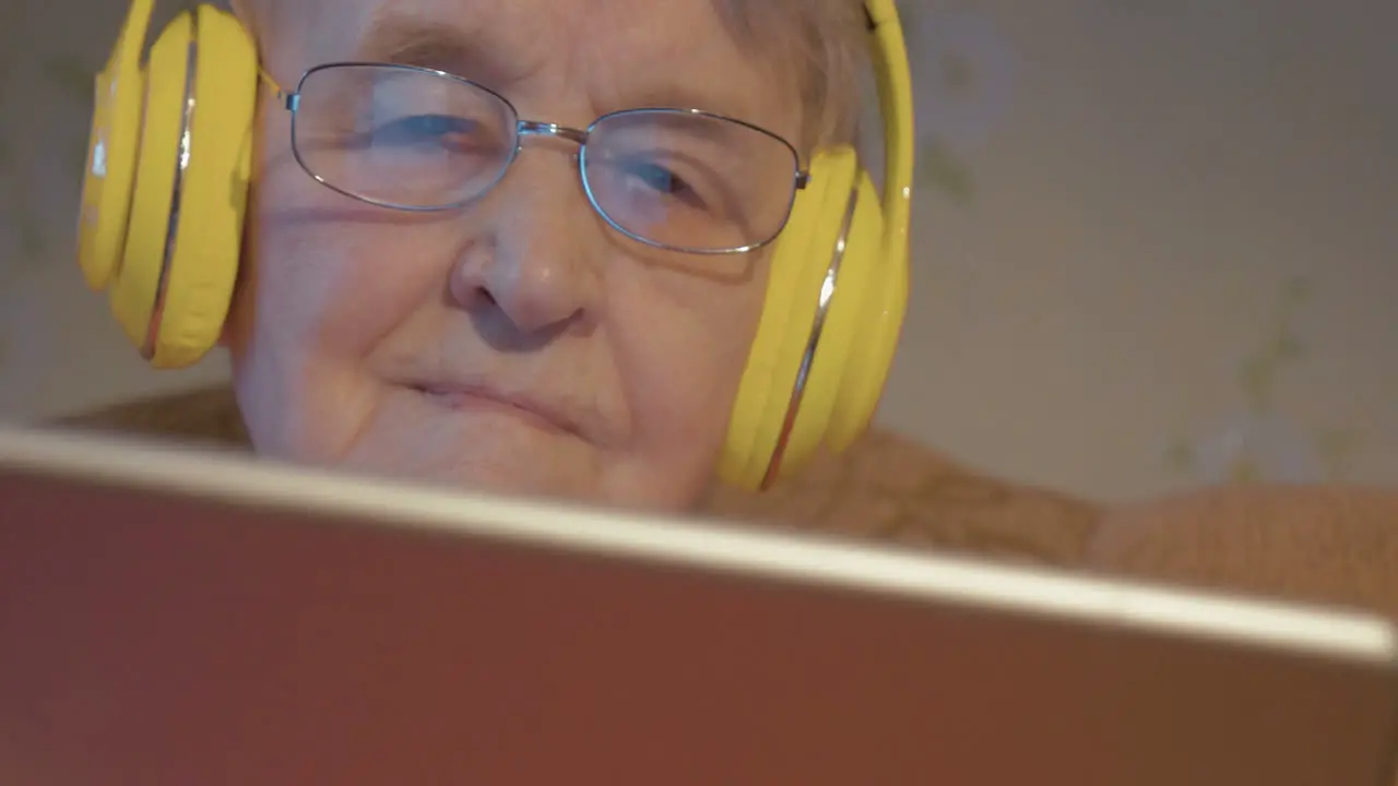 Senior woman in headphones using tablet computer