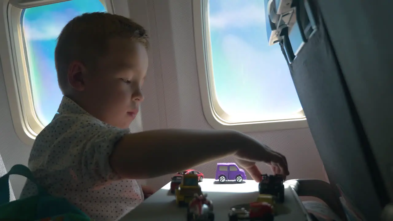 Little kid playing with toy cars in the airplane