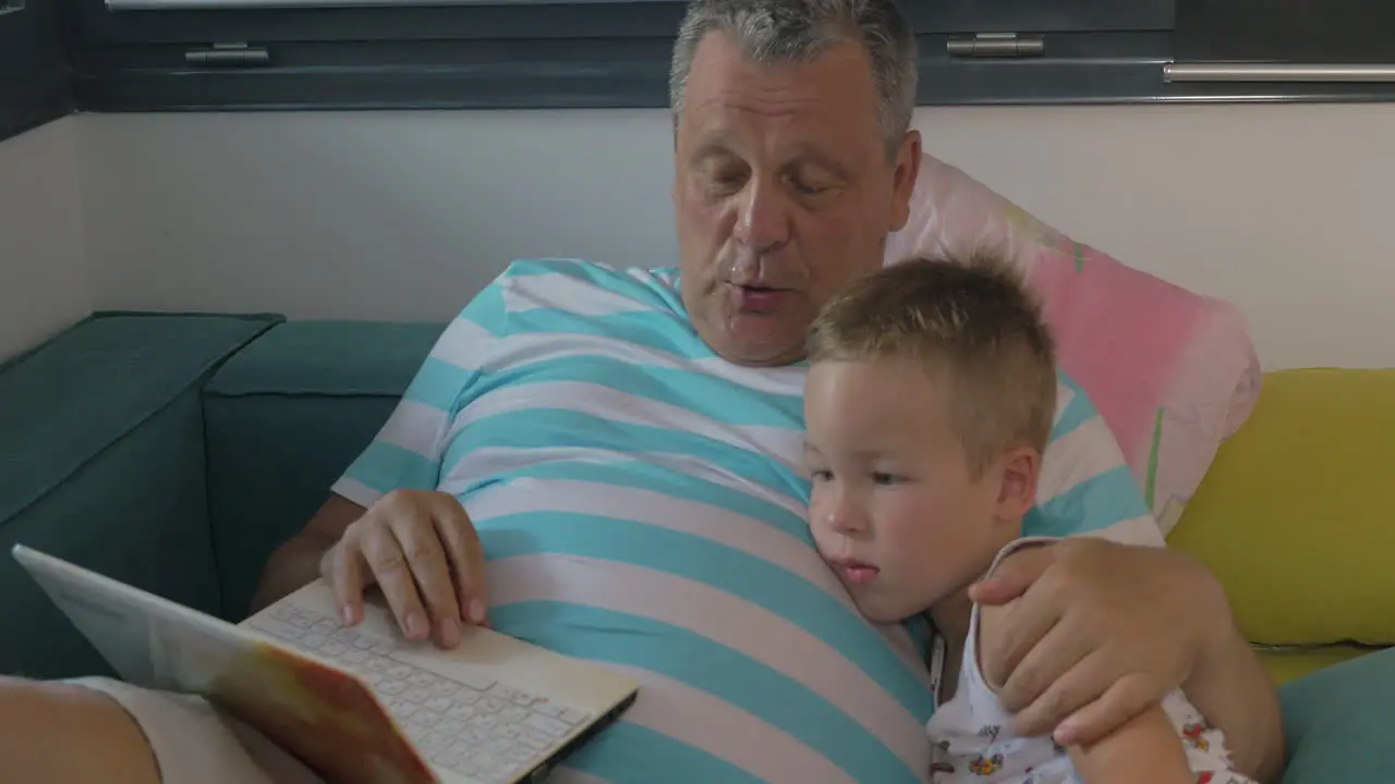 Child and grandfather using laptop at home