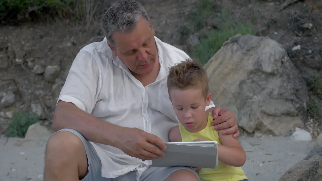 Grandson and grandfather with touch pad outdoor