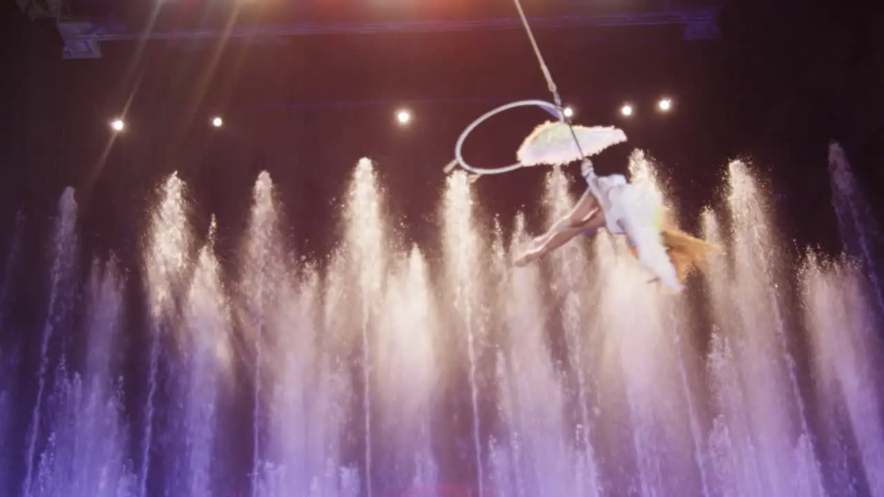 Aerial performer making acrobatic act against colorful fountains acrobatics Moscow Russia