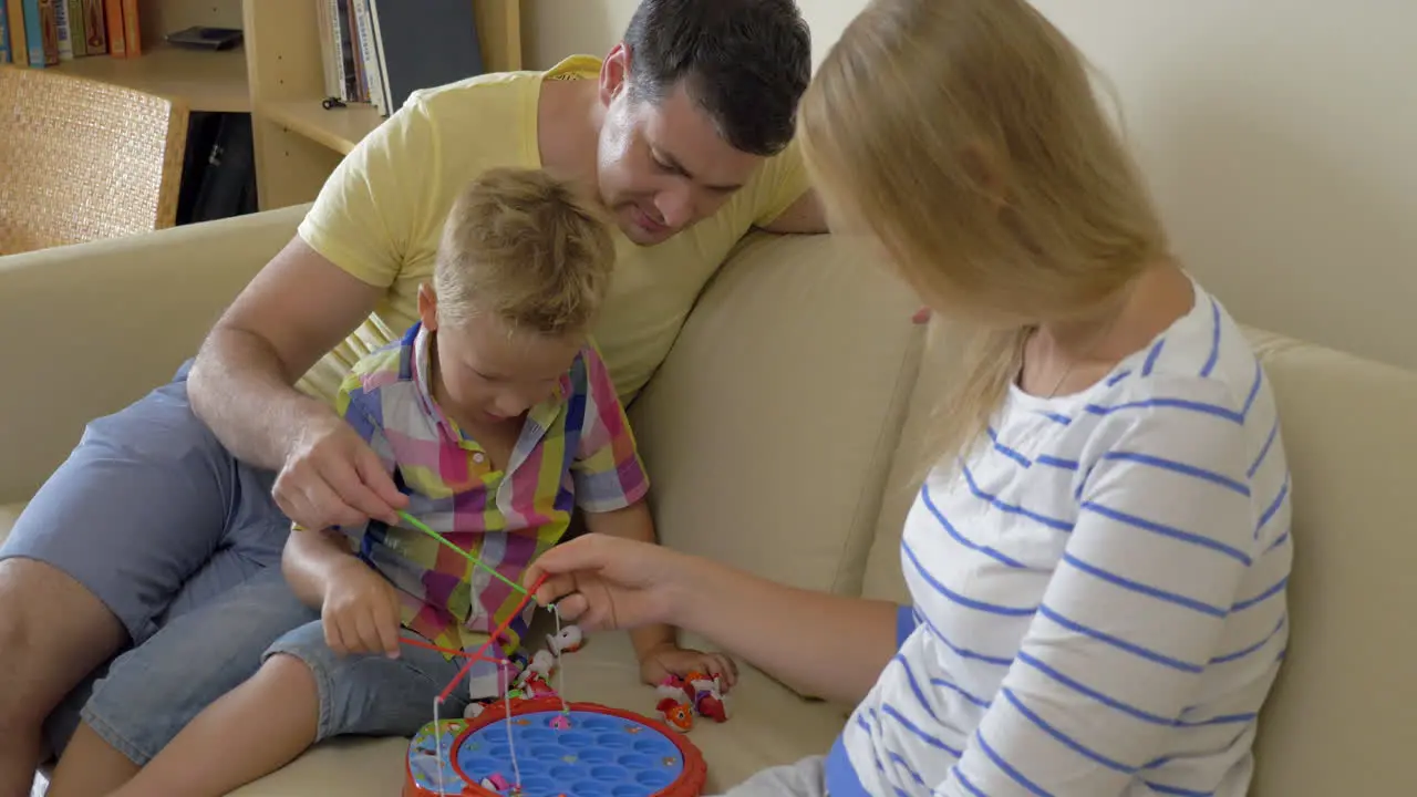 Parents and child playing fishing game at home