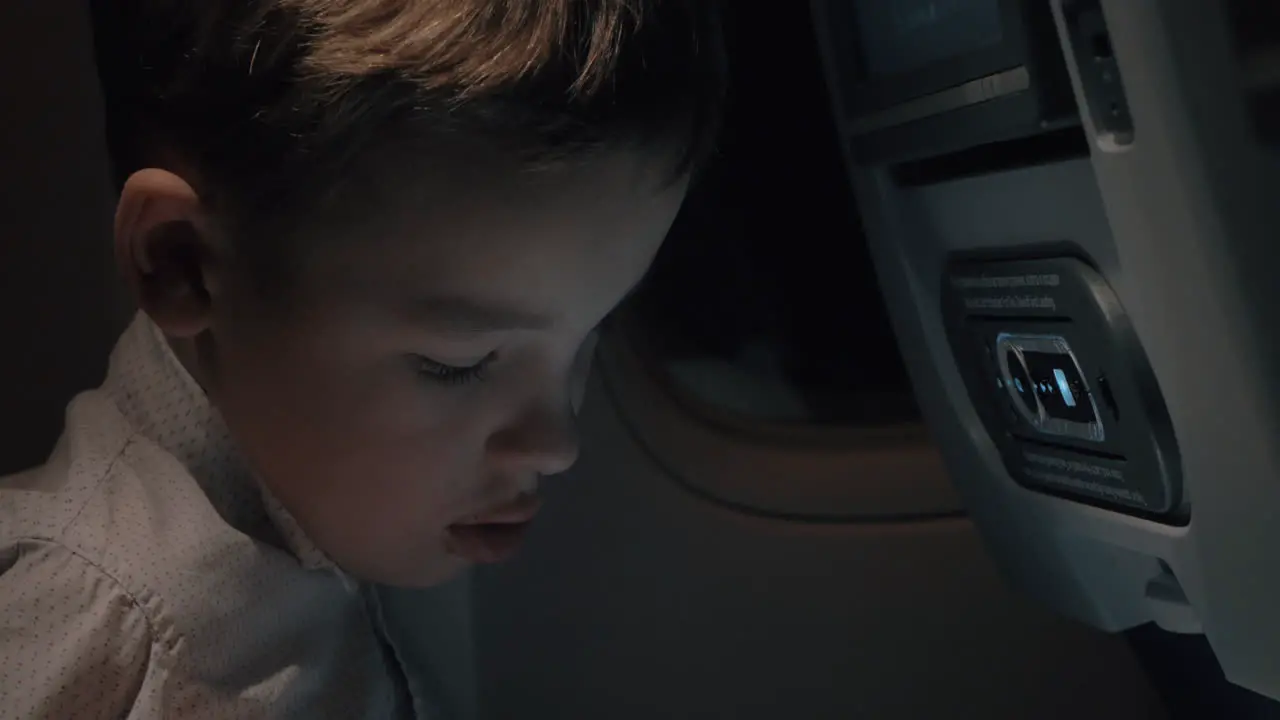 Boy playing chess on touch pad during night flight