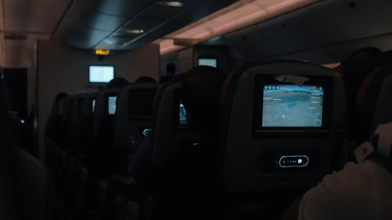 People traveling by blane at night Dark cabin with working seat monitors