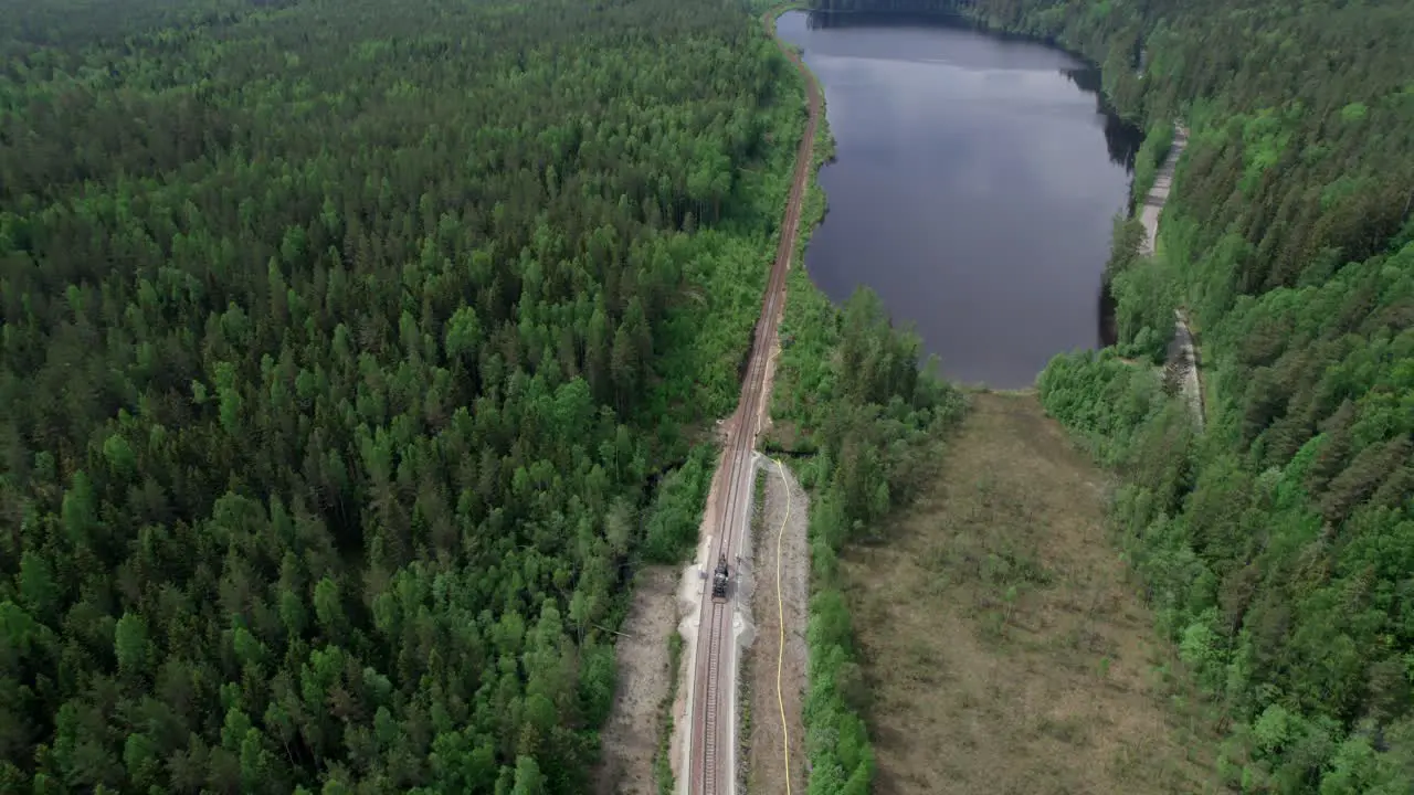 Railway Track Construction And Majestic Boreal Forest With Lake Reveal Aerial Pullback