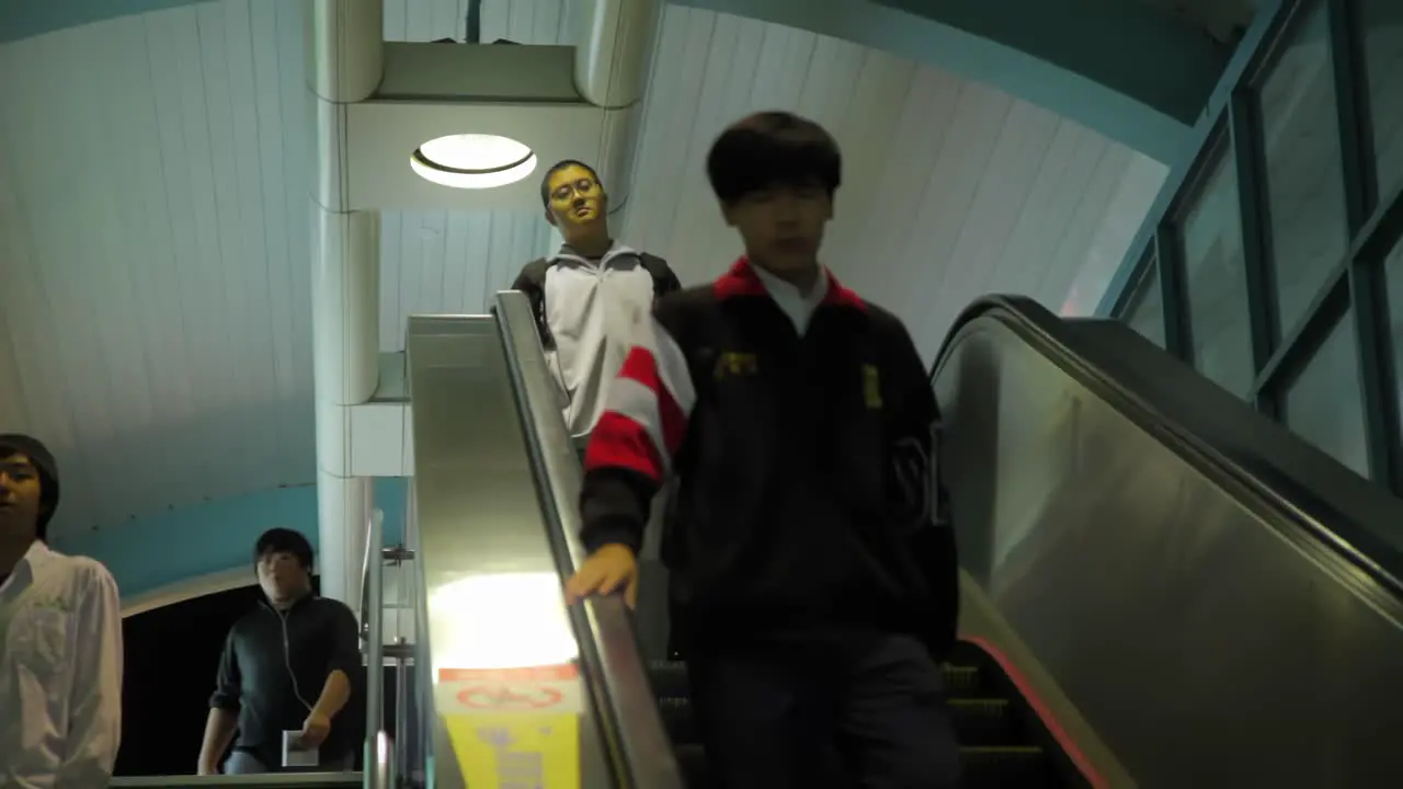 Young asian adults walking quickly down escalator stairs in Taiwan metro station