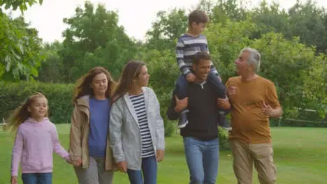 Tracking Shot of Family Walking Through Gardens Talking and Laughing 