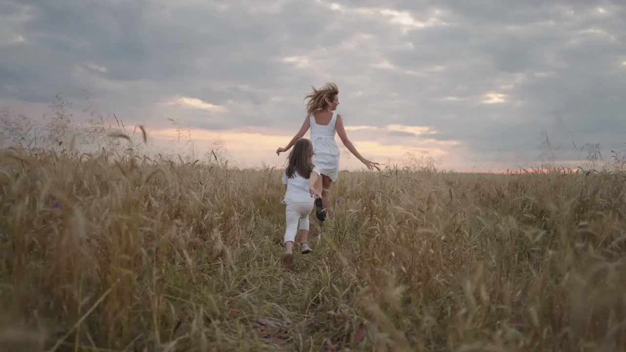 follow Daughter and mother dream together run in the wheat field at sunset happy family people in the wheat field concept Mom and girl playing catch-up run baby child fun running in green meadow