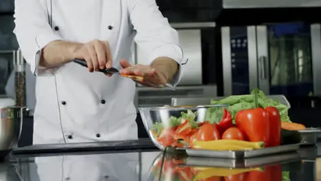 Chef cooking salad at kitchen Chef hands putting fresh vegetables in glass bowl