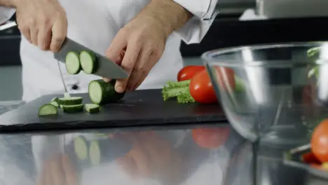 Man chef cutting cucumber at kitchen restaurant Chef hand preparing fresh salad