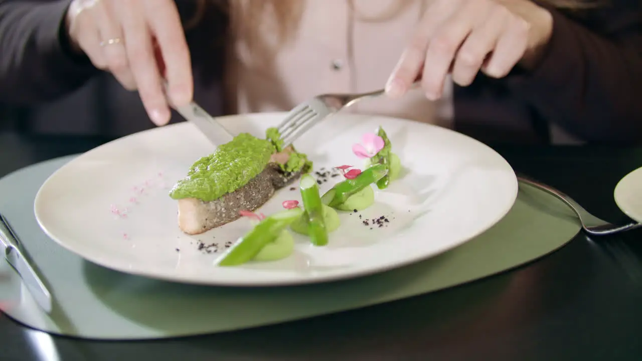 Business woman cutting fish with knife and fork at restaurant