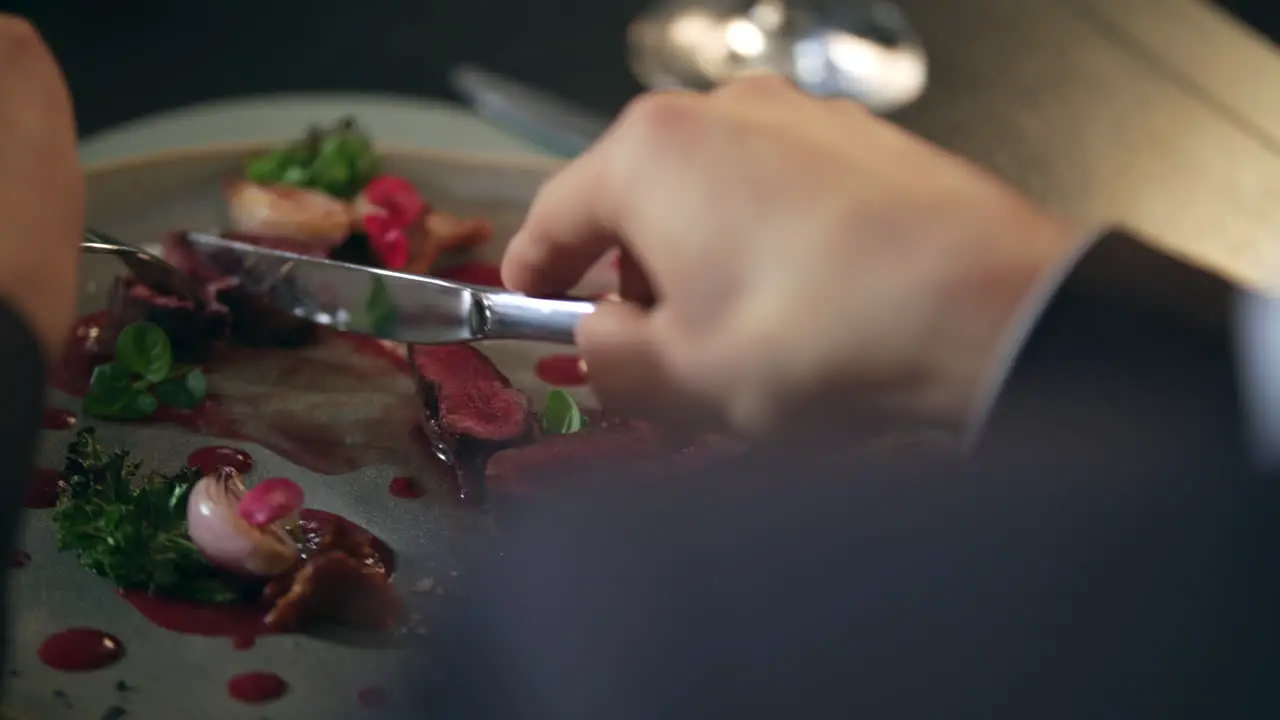 Male hands cutting food on plate in restaurant Man eating meat in restaurant