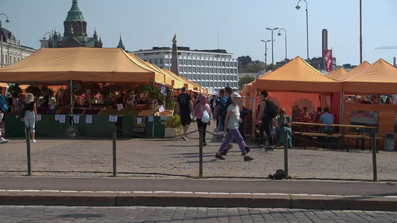 People explore outdoor food market tent stalls on Finland summer day