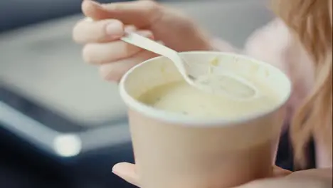 Woman eating cream soup inside the parked car