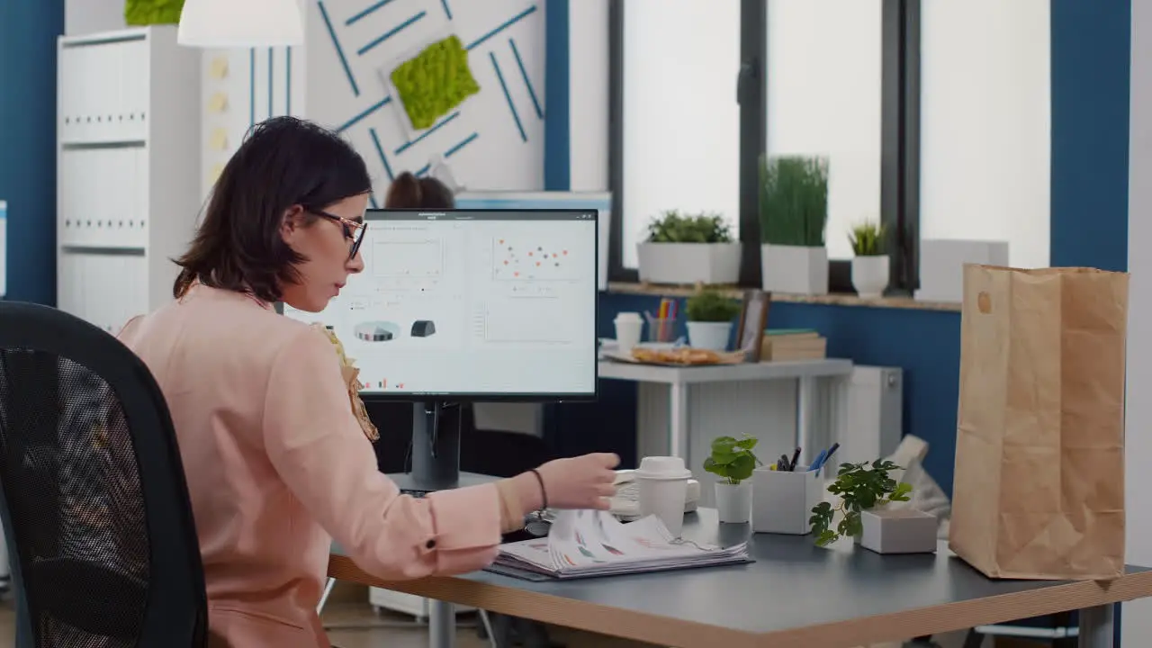 Entrepreneur woman eating tasty sandwich having food break working in business company