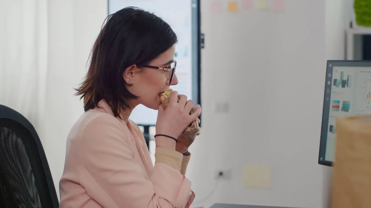 Entrepreneur woman eating tasty sandwich having meal break working in business company