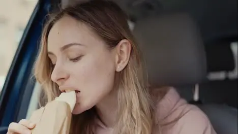 Girl having a quick snack inside the parked car