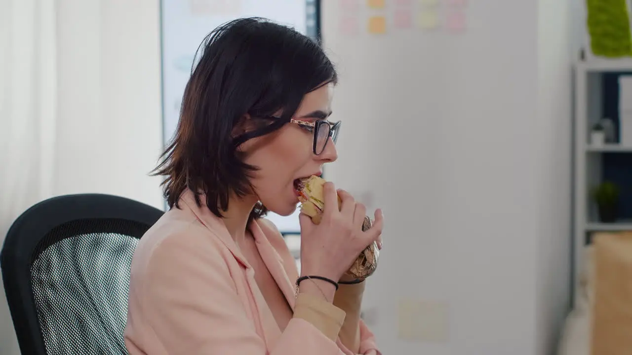 Entrepreneur woman eating tasty sandwich having work break working in business company