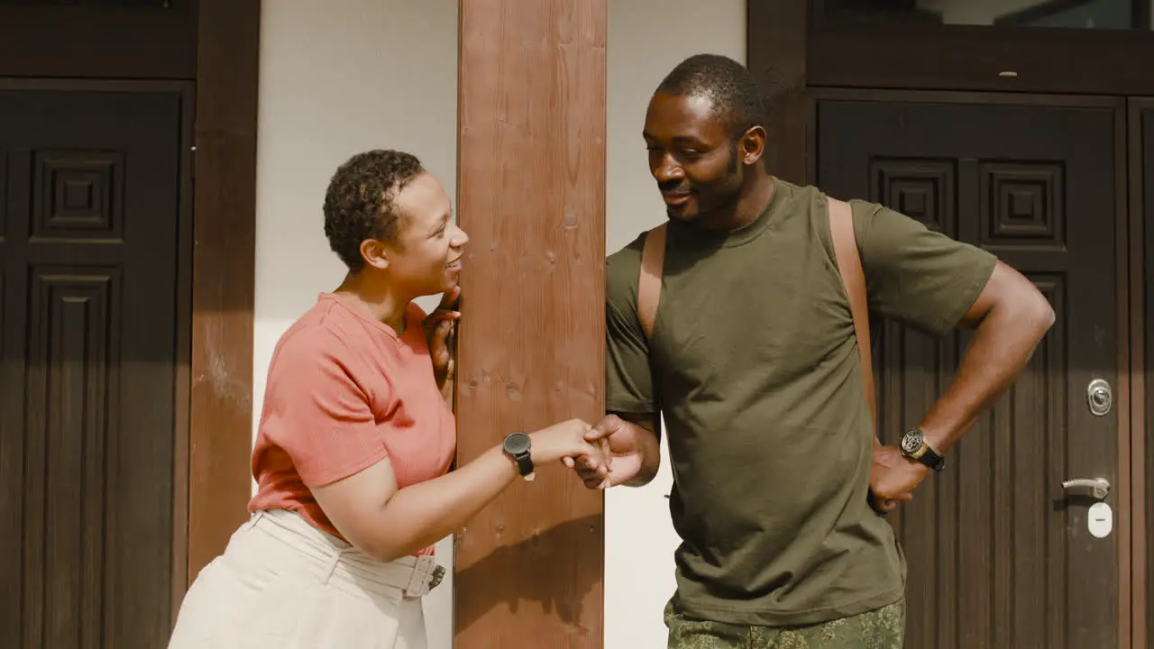 Male Soldier Holding His Wife's Hand And Talking To Her While Standing Together Outside Home In A Sunny Day