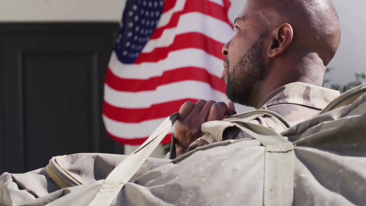 African american male soldier returning home with flag of usa at door