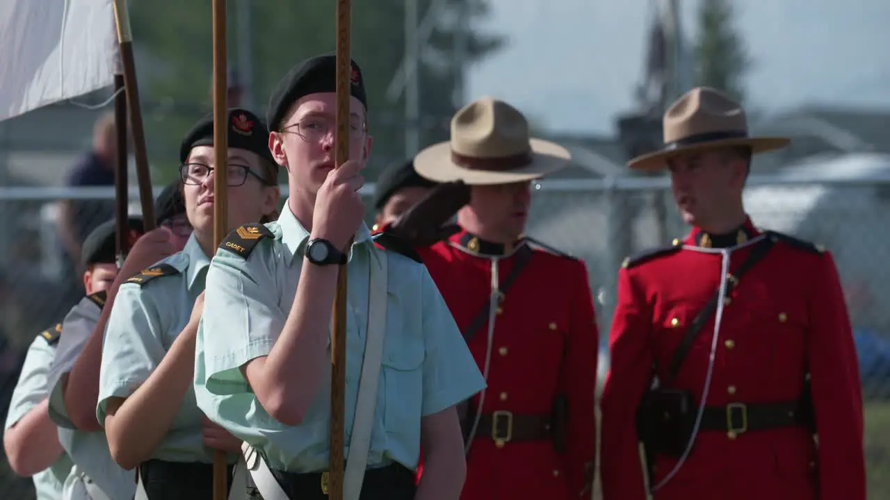 Canadian army cadets hold flags with RCMP officers in background