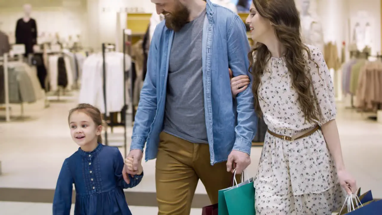 Video of happy family strolling in shopping mall