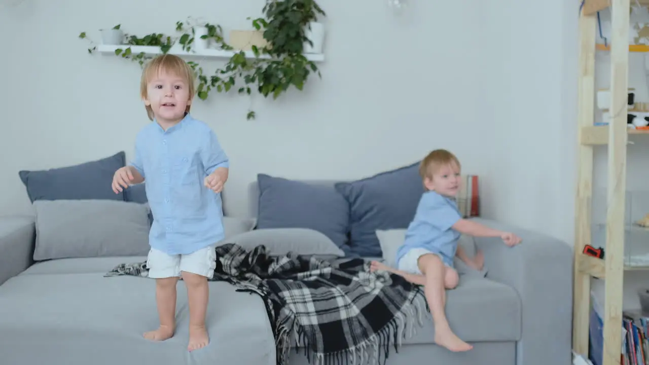 Two little boys jumping on the couch and having fun