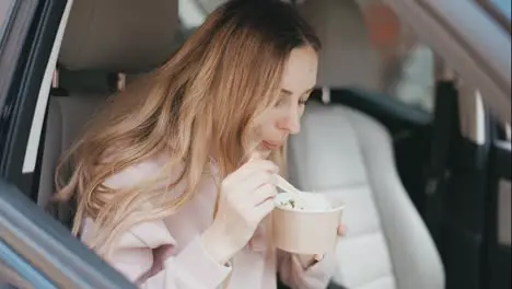 Woman eating soup inside the parked car