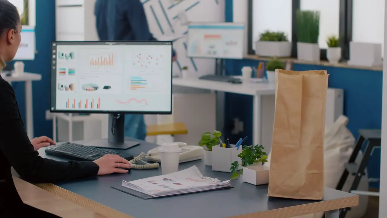 Cheerful businesswoman putting food takeaway order package on desk table during lunchtime break