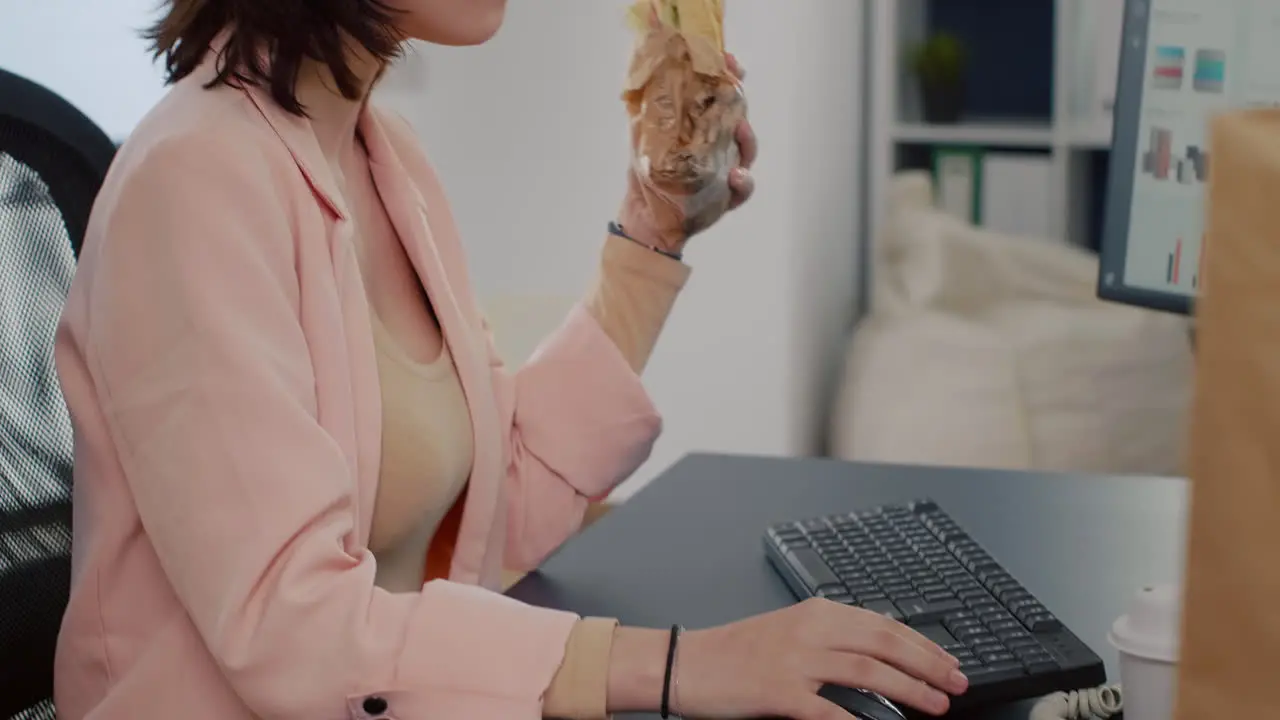 Executive manager having takeaway meal order eating tasty sandwich during lunchtime