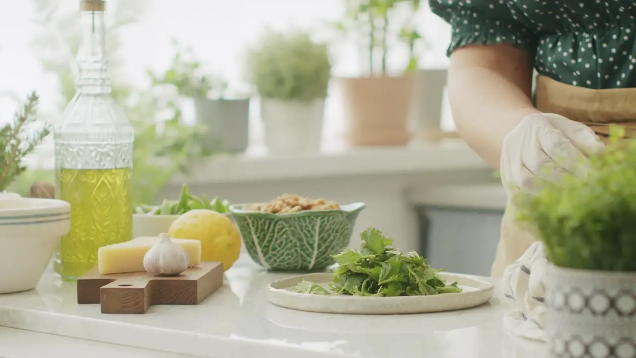 Anonymous woman tearing green basil leaves during cooking in kitchen